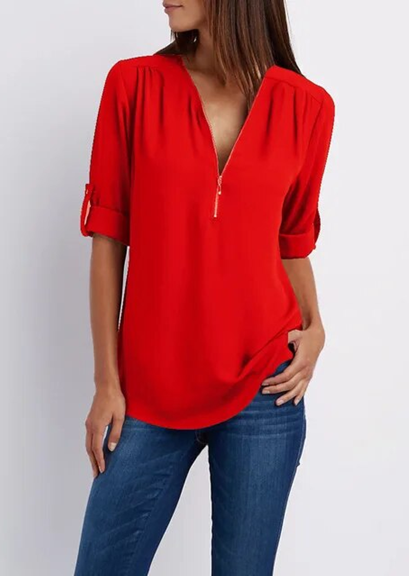 Blusa rossa da donna con zip, maniche a 3/4 arrotolate, abbinata a jeans blu. Moda casual elegante, abbigliamento femminile trendy.
