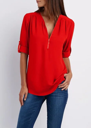 Blusa rossa da donna con zip, maniche a 3/4 arrotolate, abbinata a jeans blu. Moda casual elegante, abbigliamento femminile trendy.