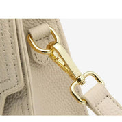 Gancio dorato su borsa in pelle beige, dettaglio elegante e lussuoso. Accessorio moda donna, chiusura sicura e resistente.
