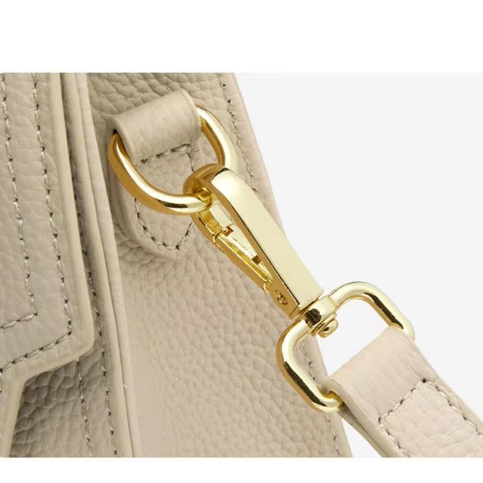 Gancio dorato su borsa in pelle beige, dettaglio elegante e lussuoso. Accessorio moda donna, chiusura sicura e resistente.
