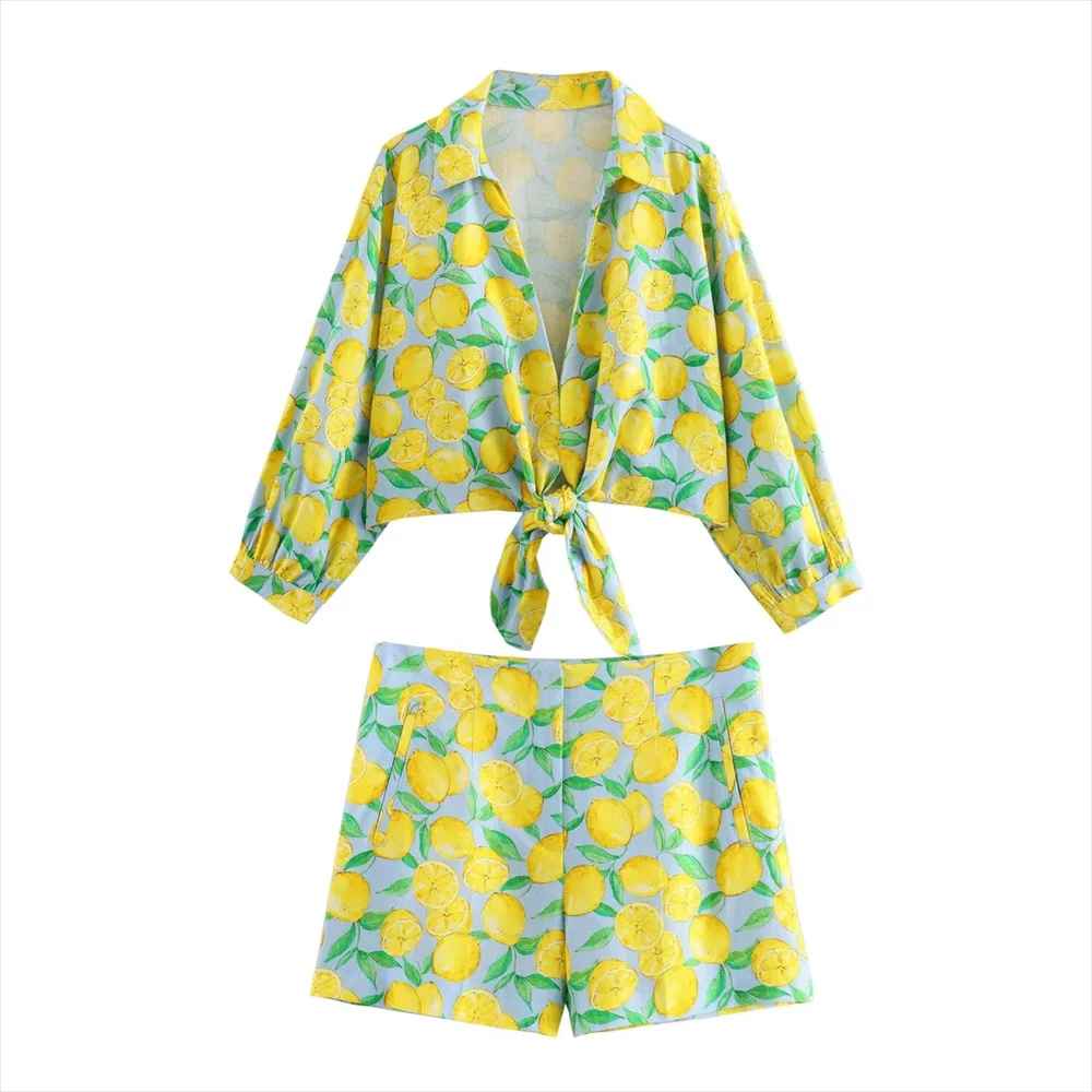 Completo estivo donna con stampa limoni, camicia annodata e pantaloncini coordinati, moda casual, colori vivaci, abbigliamento leggero.