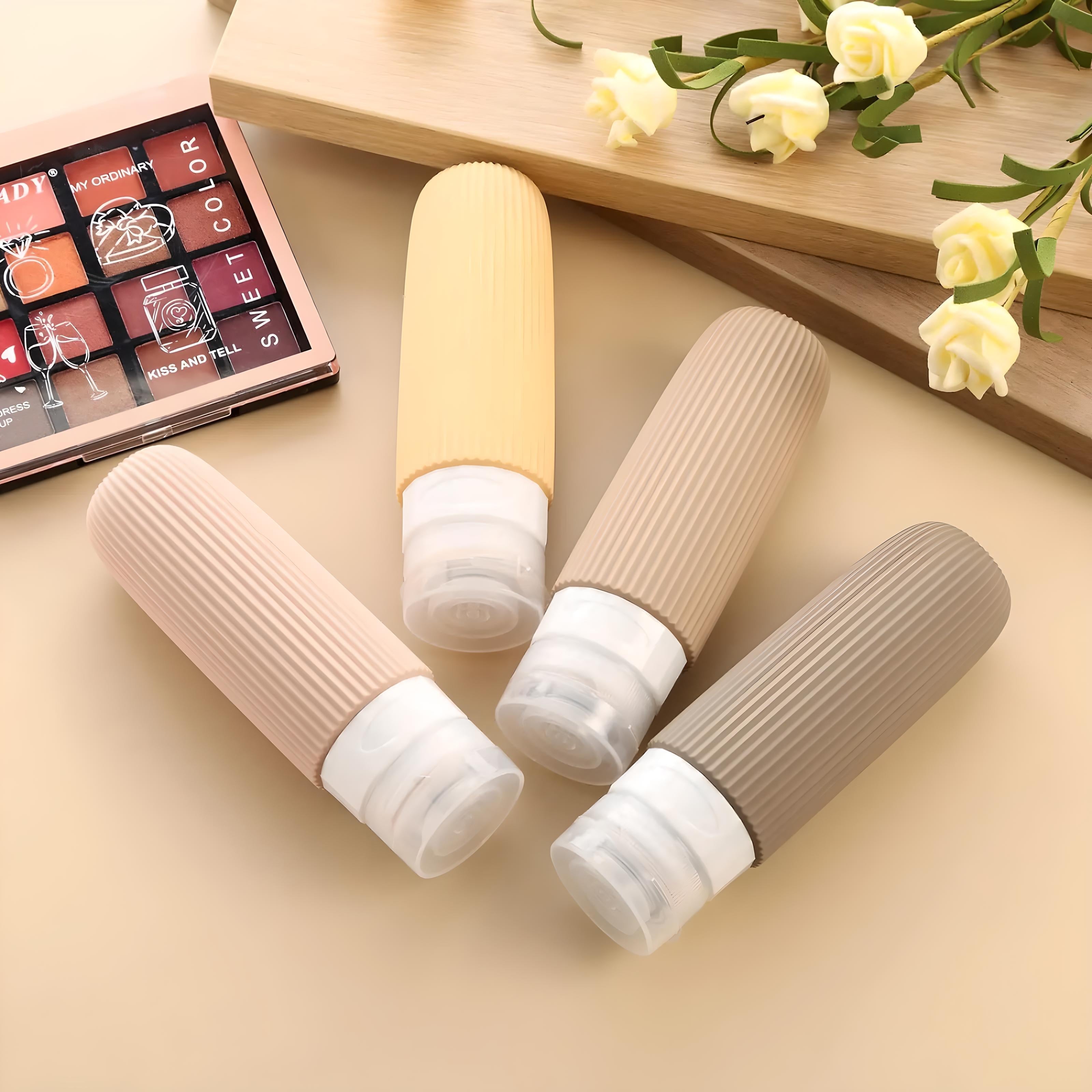Quattro flaconi da viaggio in silicone colorati su sfondo beige, ideali per cosmetici e liquidi. Accessori da viaggio pratici e riutilizzabili.