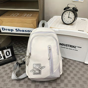 Zaino bianco moderno con logo, tasca frontale con zip, su sfondo di scatole industriali e orologio vintage. Accessorio moda unisex.