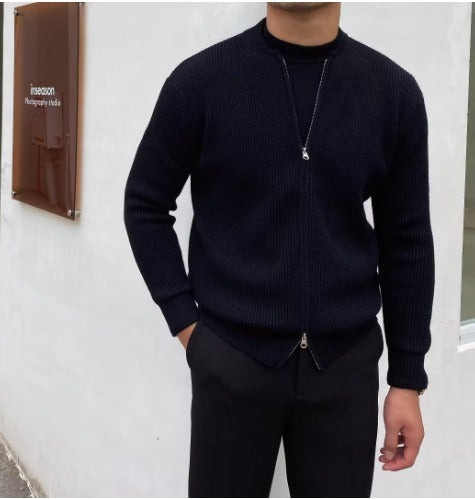 Giacca nera uomo, zip frontale, indossata con pantaloni scuri. Moda maschile elegante, abbigliamento casual autunnale. Sfondo bianco minimalista.