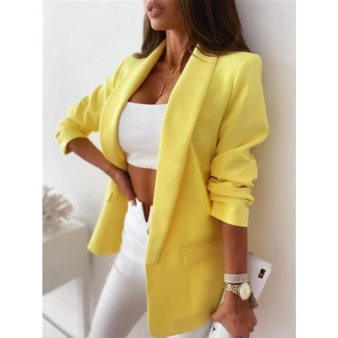 Donna con blazer giallo elegante, top bianco e pantaloni bianchi. Look moda femminile, stile casual chic. Accessori: orologio e pochette bianca.