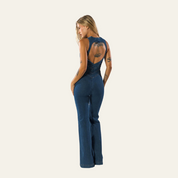 Donna in tuta jeans blu con schiena scoperta, design elegante e moderno, perfetta per moda casual e serate. Abbigliamento femminile trendy.