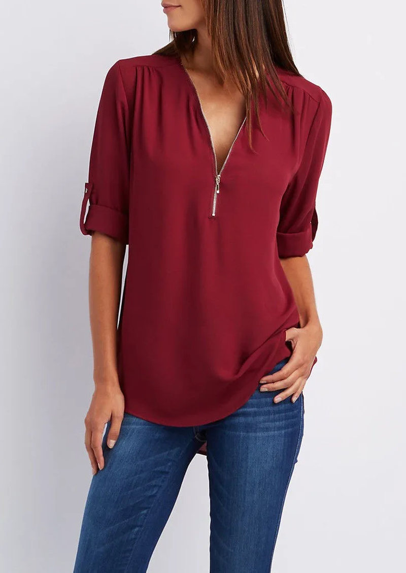 Blusa donna bordeaux con zip, maniche a 3/4 arrotolate, abbinata a jeans blu. Elegante e casual, perfetta per moda autunnale.