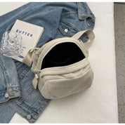 Borsa a tracolla in velluto a coste bianco su giacca di jeans, libro "Butter" e supporto trasparente. Accessorio moda casual e trendy.