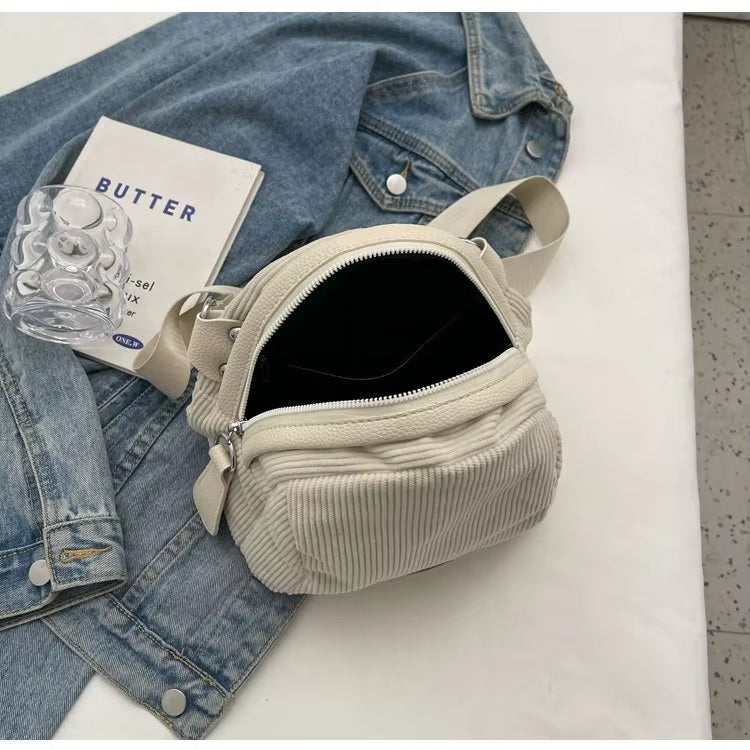 Borsa a tracolla in velluto a coste bianco su giacca di jeans, libro "Butter" e supporto trasparente. Accessorio moda casual e trendy.