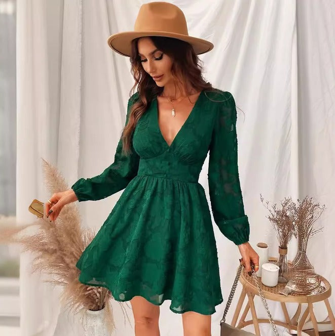 Donna con abito verde elegante, cappello beige, in posa accanto a decorazioni boho-chic. Moda femminile, stile autunnale, abbigliamento trendy.