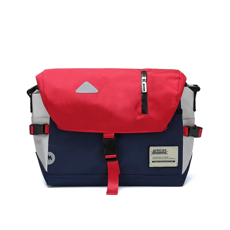 Zaino messenger multicolore con patta rossa, tasca con zip, fibbie nere e dettagli blu e grigi. Design moderno e funzionale per uso quotidiano.