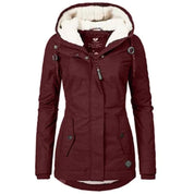 Giacca invernale donna bordeaux con cappuccio foderato in pelliccia sintetica, chiusura zip, bottoni, tasche frontali. Elegante e calda.