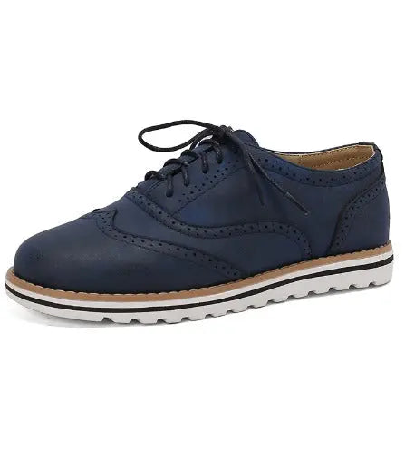 Scarpa brogue da uomo in pelle blu scuro con suola bianca dentellata, lacci neri. Elegante e casual, ideale per moda maschile e comfort.