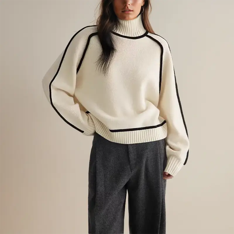 Maglione bianco a collo alto con dettagli neri, indossato con pantaloni grigi. Moda autunnale, abbigliamento casual elegante per donna.