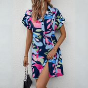 Abito chemisier estivo donna, fantasia floreale colorata, maniche corte, bottoni frontali, tessuto leggero, perfetto per look casual e vacanze.