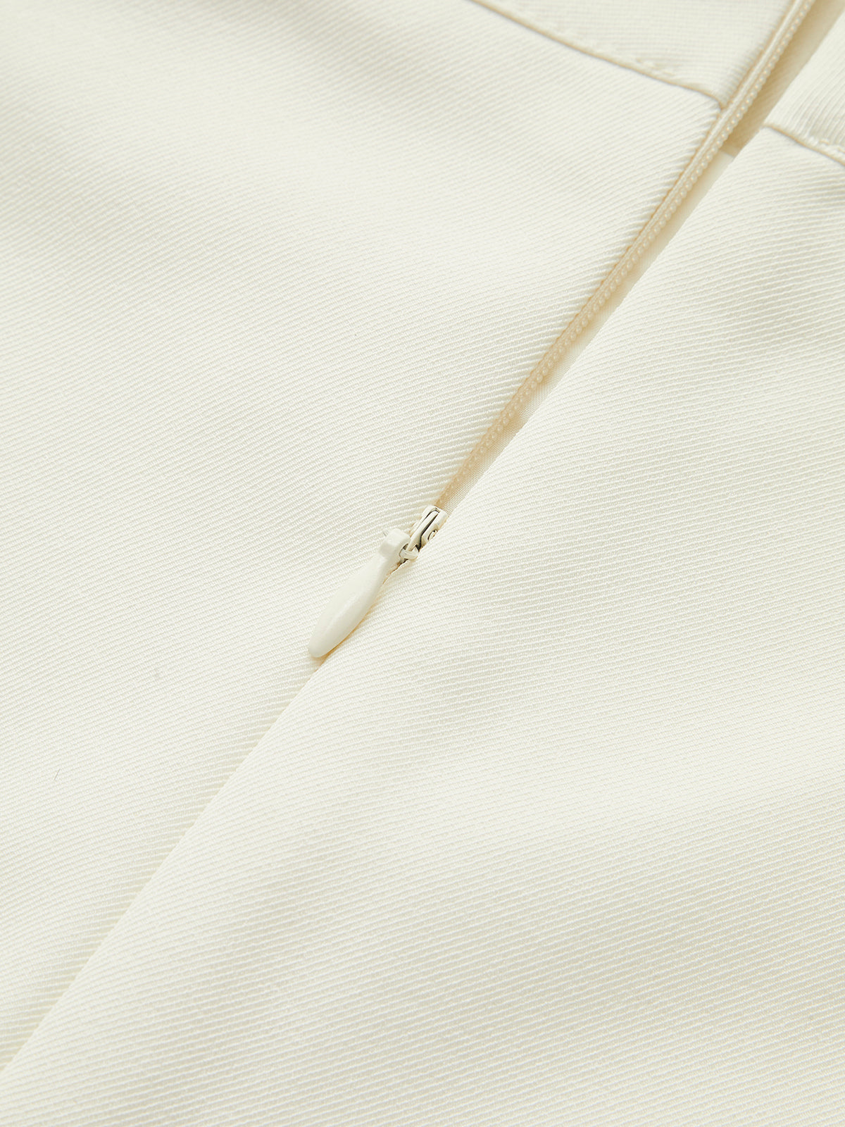 Cerniera lampo bianca su tessuto beige, dettaglio moda, chiusura abbigliamento elegante, accessorio sartoriale di alta qualità.