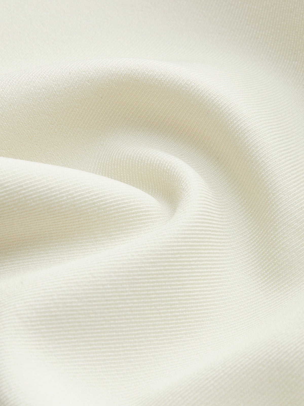 Tessuto bianco crema, texture morbida e ondulata, ideale per abbigliamento elegante e arredamento. Materiale di alta qualità, versatile e raffinato.