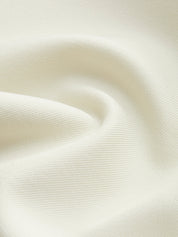 Tessuto bianco crema, texture morbida e ondulata, ideale per abbigliamento elegante e arredamento. Materiale di alta qualità, versatile e raffinato.