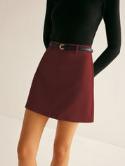Gonna corta bordeaux con cintura nera, indossata con maglia nera a maniche lunghe. Elegante e moderna, perfetta per moda autunnale.