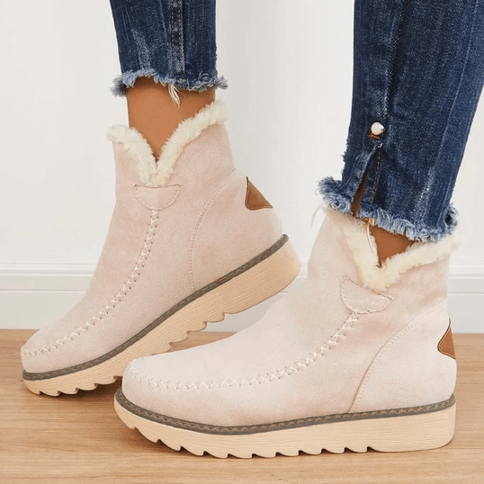 Stivaletti invernali beige da donna con fodera in pelliccia sintetica, suola in gomma antiscivolo, abbinati a jeans strappati.