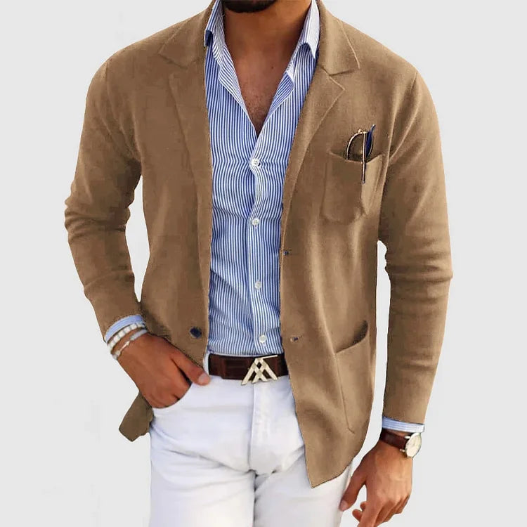 Giacca beige elegante su camicia a righe blu, abbinata a pantaloni bianchi. Look maschile sofisticato, moda uomo, abbigliamento casual chic.