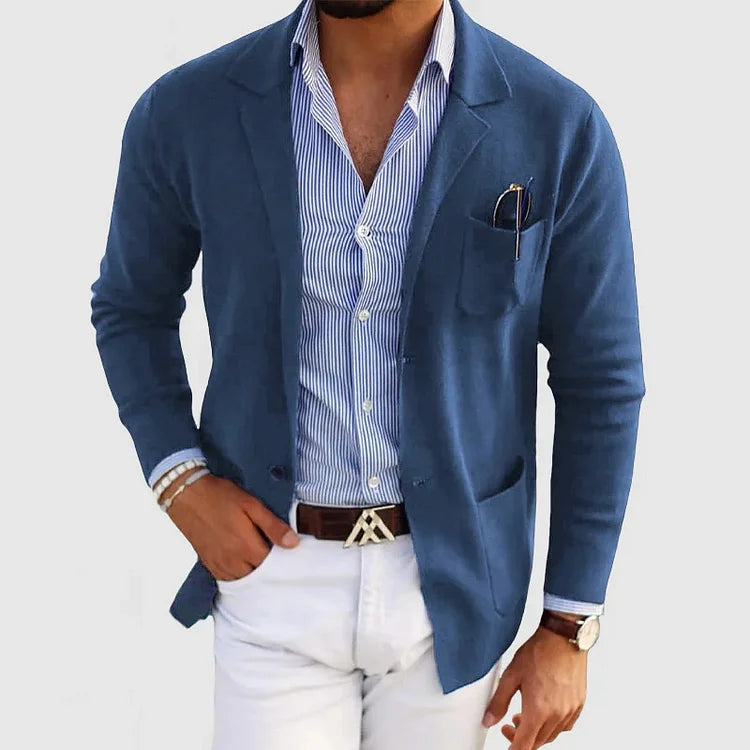 Giacca blu uomo elegante, camicia a righe, pantaloni bianchi, orologio da polso, occhiali da sole nel taschino, moda maschile casual chic.