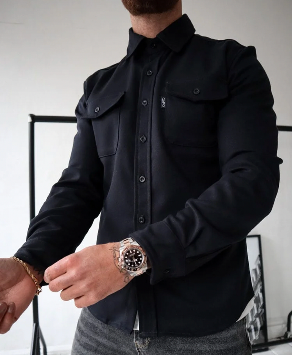 Camicia nera elegante da uomo con tasche frontali, indossata con orologio di lusso e braccialetto dorato. Stile moderno e sofisticato.