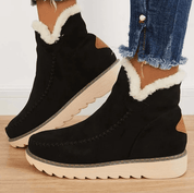 Stivaletti neri invernali da donna con fodera in pelliccia sintetica, suola in gomma beige, dettagli marroni, abbinati a jeans strappati.