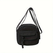 Borsa a tracolla nera in velluto a coste con tasca frontale e chiusura a zip. Design elegante e pratico, ideale per uso quotidiano e moda casual.