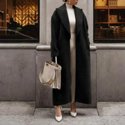 Cappotto lungo nero elegante donna, abbinato a borsa Fendi bianca e scarpe col tacco, moda autunno inverno, look sofisticato e chic.