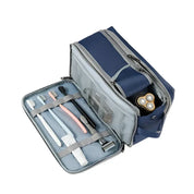Astuccio da viaggio blu con zip aperta, contenente spazzolini, rasoio e testina di rasoio elettrico. Organizzatore compatto per accessori da bagno.
