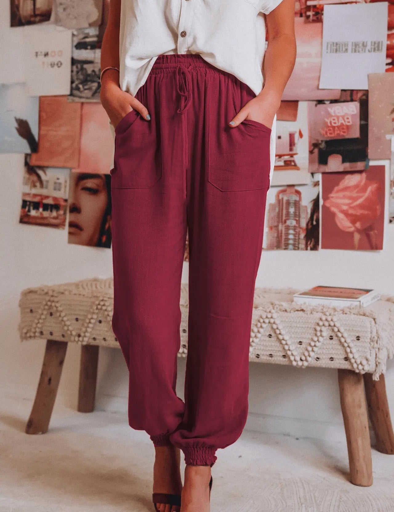 Donna in pantaloni jogger bordeaux, camicia bianca, sandali marroni. Sfondo con collage di foto. Moda casual, abbigliamento estivo donna.