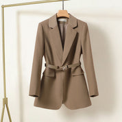 Blazer donna marrone con cintura, elegante e moderno, appeso su gruccia. Giacca sartoriale, ideale per abbigliamento formale e casual chic.