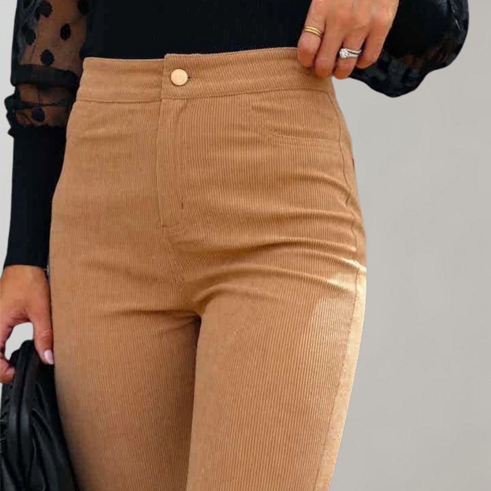 Pantaloni a vita alta in velluto a coste beige, chiusura con bottone, indossati con maglia nera. Stile elegante e moderno per donna.