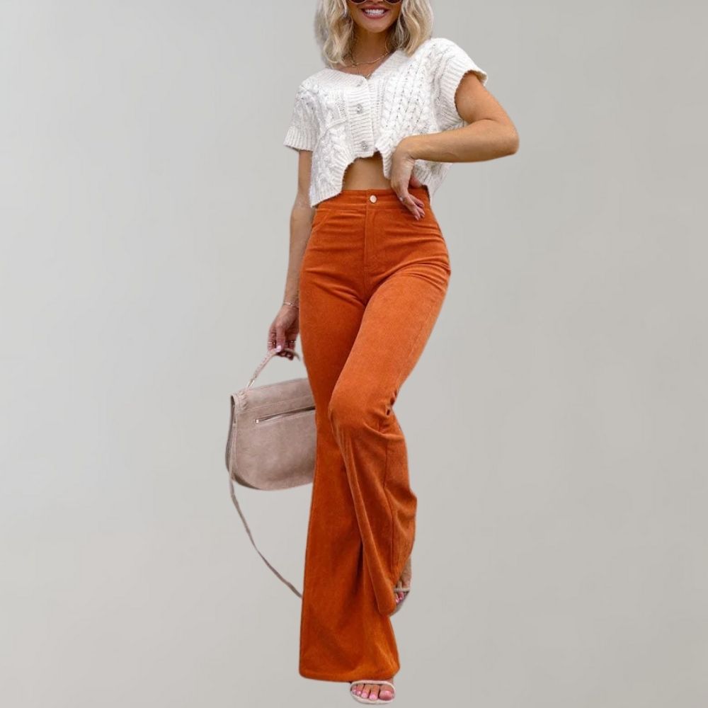 Donna con pantaloni a zampa arancioni e top bianco lavorato a maglia, borsa a tracolla rosa. Moda autunnale casual chic.