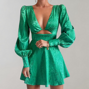 Abito verde elegante con scollo a V profondo, maniche lunghe a sbuffo e dettaglio cut-out in vita. Perfetto per eventi serali e moda femminile.
