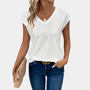 Donna con maglietta bianca a V, jeans blu e borsa beige. Moda casual estiva, abbigliamento femminile trendy, accessori eleganti.