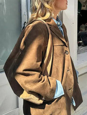 Giacca in pelle scamosciata marrone da donna, stile casual, abbinata a camicia di jeans. Moda autunnale, abbigliamento femminile elegante.
