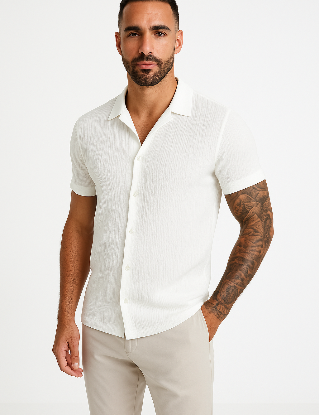 Uomo con camicia bianca a maniche corte, tessuto leggero, abbinata a pantaloni beige. Moda estiva elegante, stile casual chic.
