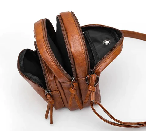 Zaino in pelle marrone con tre scomparti aperti, cerniere robuste e tracolla regolabile. Design elegante e funzionale per moda e praticità.