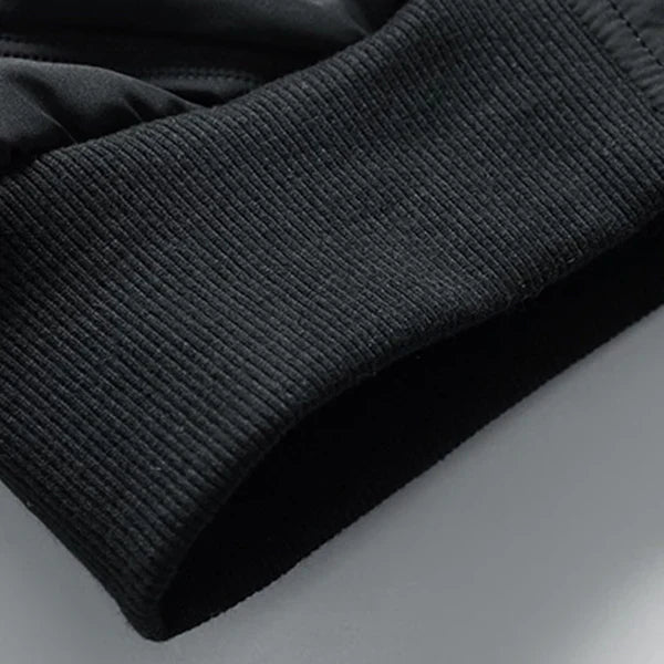 Polsino elastico nero in tessuto a coste, dettaglio di una felpa sportiva. Design moderno, ideale per abbigliamento casual e sportivo.