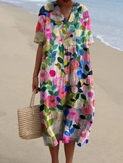 Abito estivo floreale colorato, maniche corte, scollo a V, indossato su spiaggia sabbiosa. Moda donna, abbigliamento casual, stile boho chic.