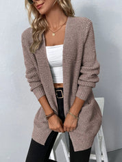 Donna con cardigan lavorato a maglia beige, top bianco e jeans neri. Moda autunnale, abbigliamento casual elegante, stile femminile moderno.