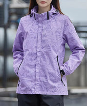 Giacca impermeabile donna viola con motivo foglie, cappuccio regolabile e tasche con zip. Ideale per outdoor e attività sportive.