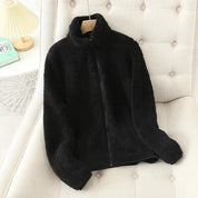 Giacca in pile nero su sedia beige, design morbido e caldo, ideale per l'inverno. Moda casual, abbigliamento donna, stile confortevole.