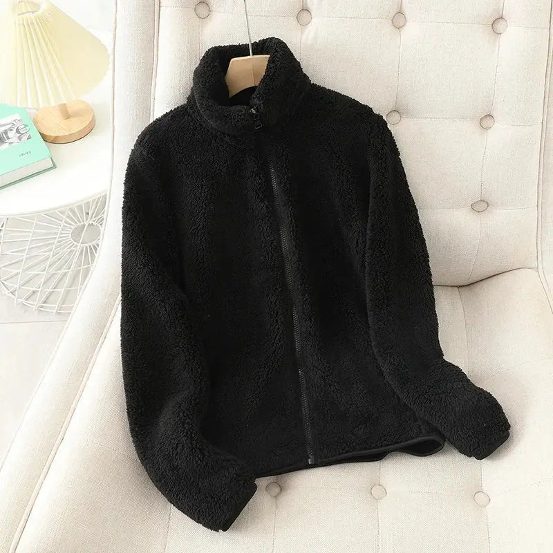 Giacca in pile nero su sedia beige, design morbido e caldo, ideale per l'inverno. Moda casual, abbigliamento donna, stile confortevole.