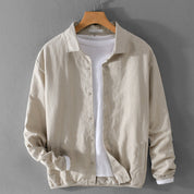 Giacca beige in lino su gruccia, abbinata a maglietta bianca. Moda uomo, abbigliamento casual, stile elegante. Perfetta per primavera e autunno.