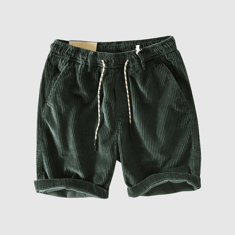 Pantaloncini corti in velluto a coste verde scuro con coulisse, tasche laterali e orlo risvoltato. Stile casual estivo per uomo.