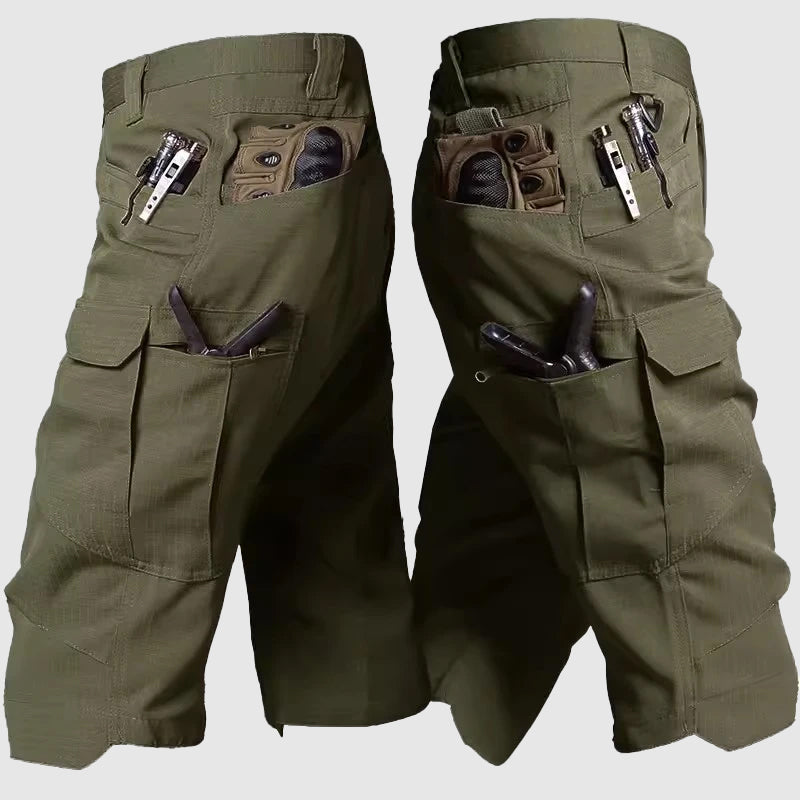 Pantaloncini tattici verdi con tasche multiple, cerniere e passanti per attrezzi. Ideali per attività outdoor e avventure all'aperto.