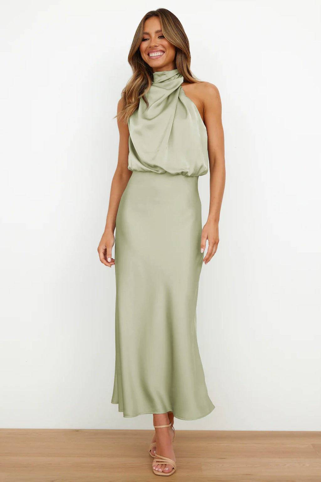 Abito lungo verde salvia in raso con scollo all'americana, indossato da una donna sorridente. Elegante, moda femminile, abbigliamento estivo.
